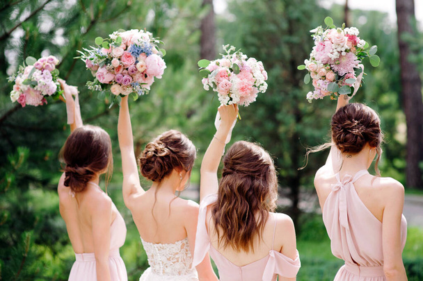Zomer bruiloft. Bruidsmeisjes in roze jurken en bruid met prachtige boeketten. Mooi luxe bruiloft blog concept. - Foto, afbeelding
