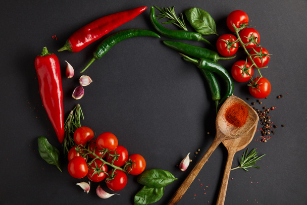 acostado plano con tomates rojos cereza, dientes de ajo, romero, granos de pimienta, hojas de albahaca y chiles verdes en negro
 - Foto, Imagen