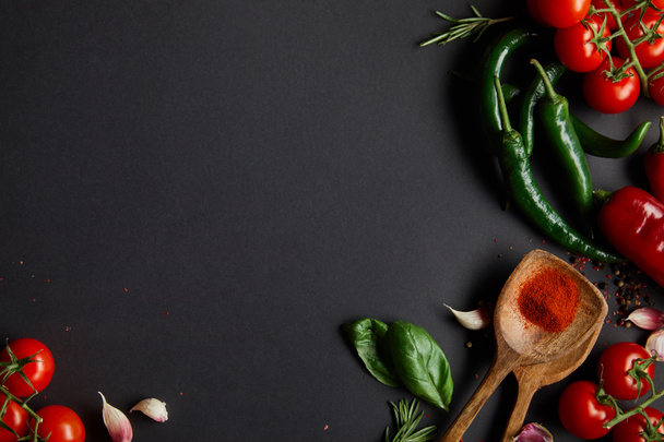 top view of organic cherry tomatoes, garlic cloves, fresh rosemary, peppercorns, basil leaves and green chili peppers on black - Φωτογραφία, εικόνα