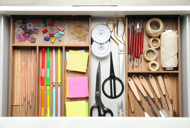 Sewing accessories and stationery in open desk drawer, top view - Φωτογραφία, εικόνα