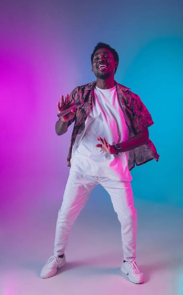 African-american male singer portrait isolated on gradient studio background in neon light - Photo, Image