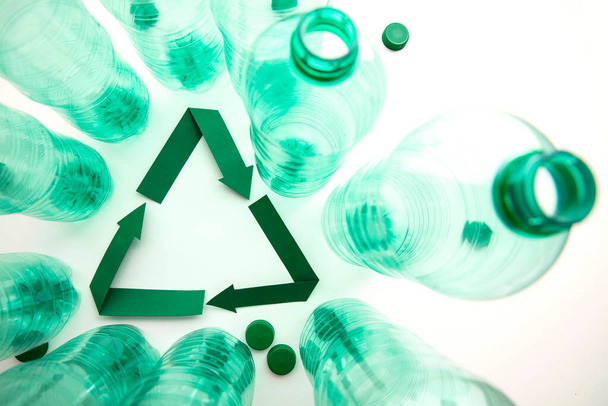 Green paper recycling symbol with empty plastic water bottles - Foto, Bild