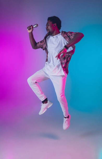 African-american male singer portrait isolated on gradient studio background in neon light - Foto, Imagen