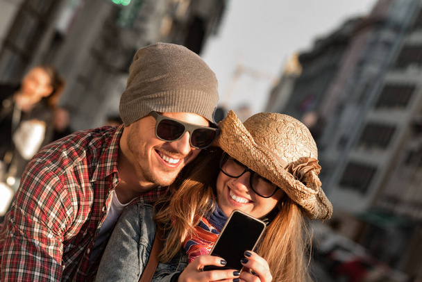 Jovem casal turístico usando smartphone no ambiente urbano da cidade para tirar fotos
. - Foto, Imagem