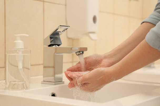 Woman washing hands with antiseptic soap in bathroom, closeup. Virus prevention - Photo, Image