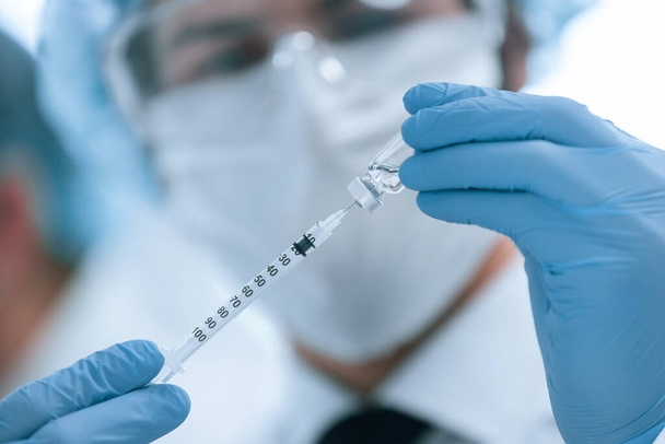 close up. scientist filling the syringe with the new vaccine . - Foto, Bild