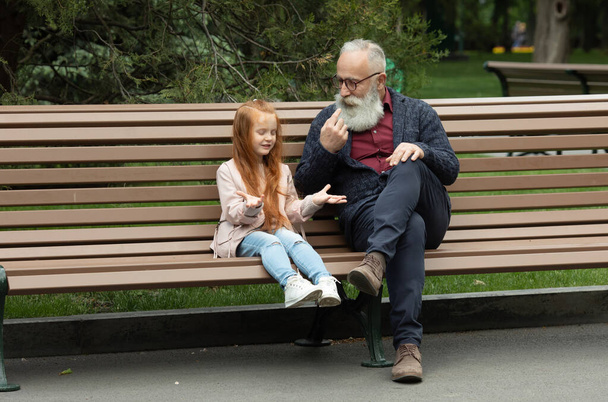 Adorable little girl laughing happily while his bearded grandfather. Emotions expressive together family childhood parenting communication interacting lifestyle. - Фото, изображение