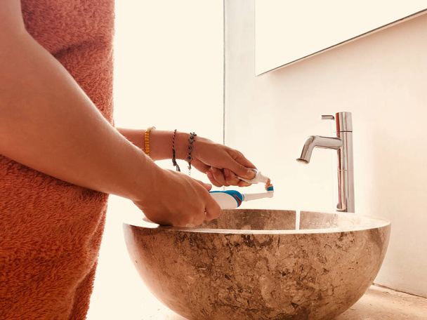 Женщина с помощью зубной щетки в светлой ванной комнате. - Фото, изображение