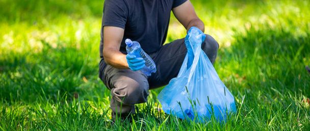 Man picking up plastic bottle, garbage collecting in a forest cleaning planet, help garbage collection charity environment - Foto, imagen