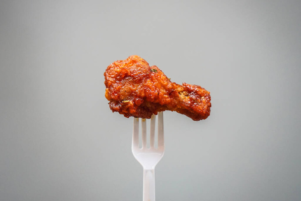 gebakken kip op plastic vork met grijze achtergrond, fast food Concept met kopieerruimte.  - Foto, afbeelding