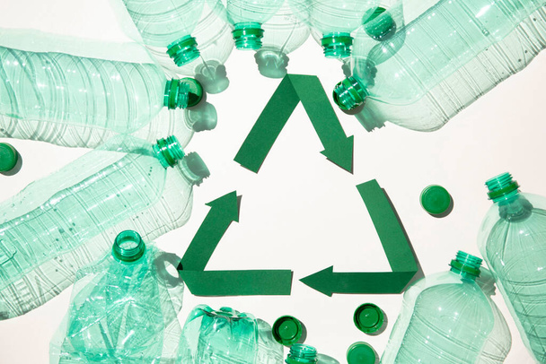 Green paper recycling symbol with empty plastic water bottles - Foto, Bild