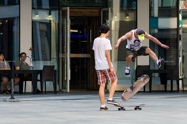 Beijing / China - August 21, 2016: Skaters doing tricks with skateboards in modern Sanlitun area of Chaoyang district in central Beijing, China - Photo, Image