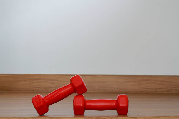 Red modern dumbbells on a wooden floor - Photo, Image
