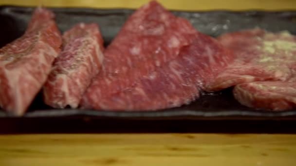 4K, Thinly sliced Japanese wagyu beef on grille for barbecue. Grill one of the best beef in Japan. Style Yakiniku meaning grilled meat cuisine. BBQ food.-Dan - Materiał filmowy, wideo
