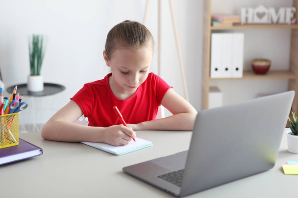 A child learns online at home through a modern laptop on the Internet. - 写真・画像