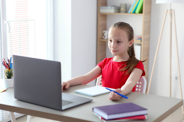Uma criança aprende on-line em casa através de um laptop moderno na Internet
. - Foto, Imagem