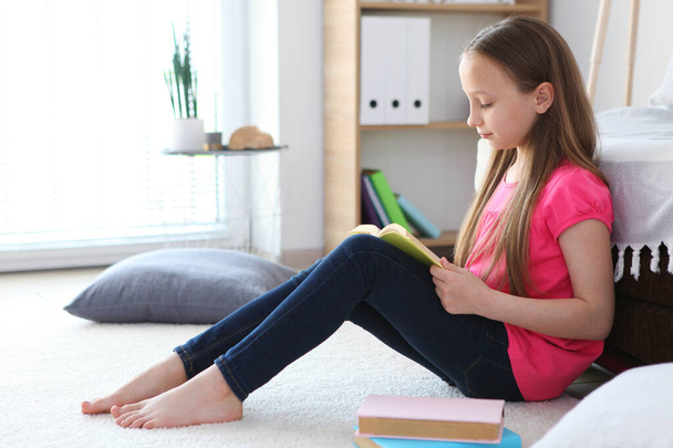little girl reads a book at home - Φωτογραφία, εικόνα
