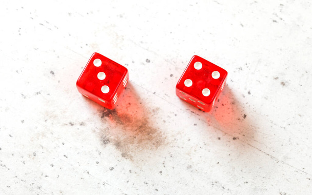 Two red craps dices showing Natural or Seven Out (number 3 and 4) overhead shot on white board - Foto, imagen