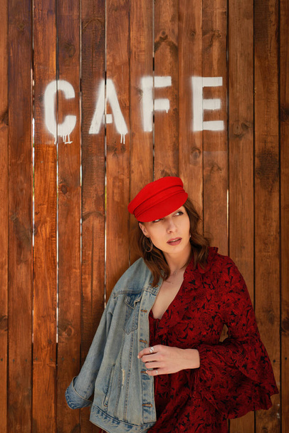 Portrait fashionable woman in red cap on wood background - Фото, зображення