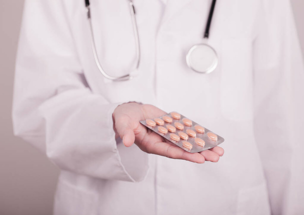 Doctor holding strip of pills on light hospital wall background. Antibiotics, vitamins and virus treatment tablet. - Valokuva, kuva