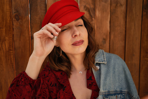 Portrait fashionable woman in red cap on wood background - Fotó, kép