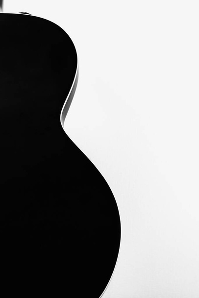 Guitare rock électrique noire forme lisse silhouette sur fond blanc mural.Jazz rockabilly archtop guitare. Photo verticale
 - Photo, image