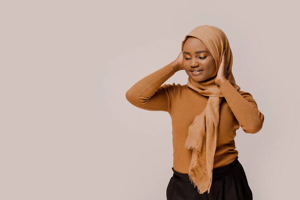 Mujer árabe musulmana africana en hijab tradicional sobre fondo blanco estudio tímido y endereza la ropa. Estilo de vida. Culturas del mundo. Fotos con espacio de copia lugar
.  - Foto, imagen