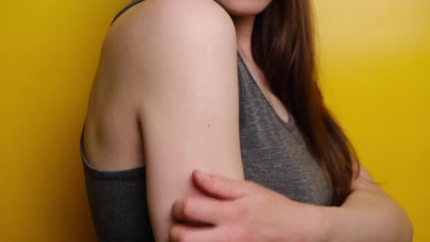 Πλευρική άποψη του περικοπεί νεαρή γυναίκα ξύσιμο μια φαγούρα με το χέρι εξωτερική, στέκεται πάνω από κίτρινο φόντο στούντιο. Γρατζουνιά στο χέρι κορίτσι από αλλεργία. Ευαίσθητο δέρμα, συμπτώματα τροφικής αλλεργίας, Ερεθισμός - Πλάνα, βίντεο