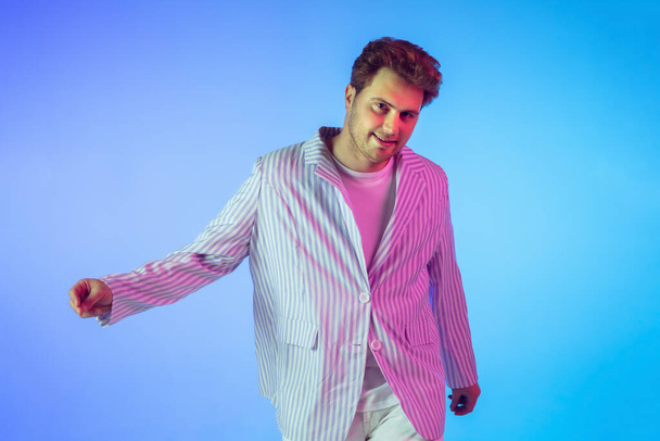 Young caucasian musician, dancer, party host, DJ on gradient background in neon light - Valokuva, kuva
