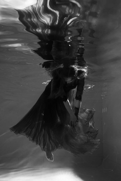 Beautiful girl underwater in a red dress swims in the pool. Tenderness and elegance. Bubbles and a lot of water - Valokuva, kuva