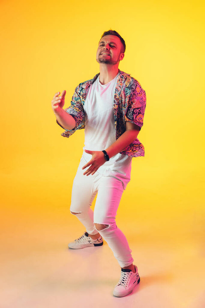 Young caucasian musician, dancer, party host, DJ on gradient background in neon light - 写真・画像