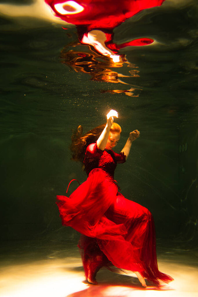 Beautiful girl underwater in a red dress swims in the pool. Tenderness and elegance. Bubbles and a lot of water - Fotografie, Obrázek
