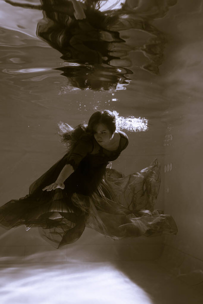 Beautiful girl underwater in a red dress swims in the pool. Tenderness and elegance. Bubbles and a lot of water - Φωτογραφία, εικόνα