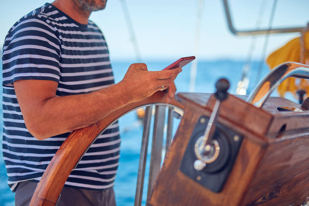 Sailing boat captain using smartphone for navigation on the open sea. - Фото, зображення