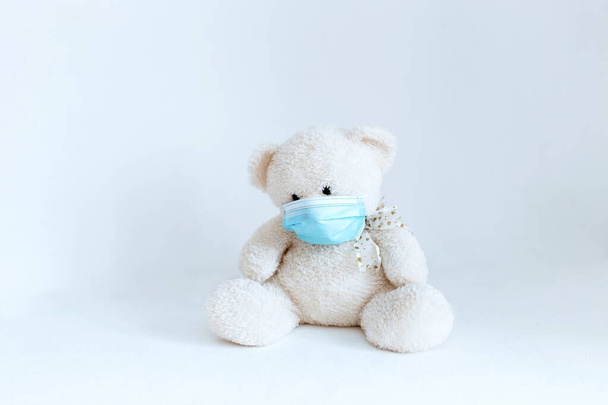 juguete suave con una máscara médica quitada sobre un fondo blanco
 - Foto, Imagen
