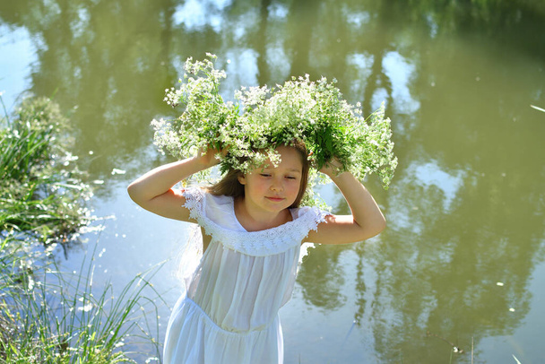 Girl in beautiful wreath on summer meadow near the river . Feast of Ivan Kupala.Midsummer.7th July, traditional slavic holiday with fortune-telling and divination rituals in Ukraine.Selective focus - Photo, Image