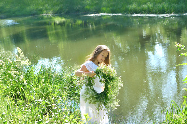 Lány gyönyörű koszorúval a nyári réten, a folyó mellett. Ünnepe Ivan Kupala.Szentiván.Július 7., hagyományos rabszolga ünnep jövendőmondó és jövendölési rituálék Ukrajnában.Szelektív fókusz - Fotó, kép