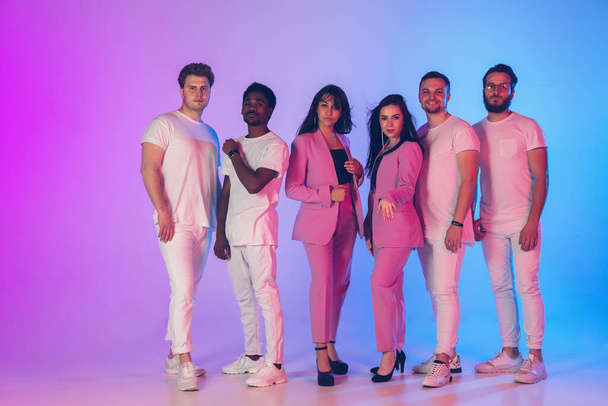 Group of young multiethnic musicians created band, posing in neon light on gradient background - Zdjęcie, obraz