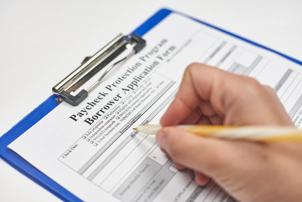 Una persona llenando el formulario de solicitud. Solicite el Programa de Protección de cheque de pago con un prestamista elegible
 - Foto, Imagen
