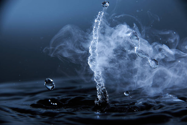 Boiling water splash with steam on dark blue background closeup. - Foto, immagini