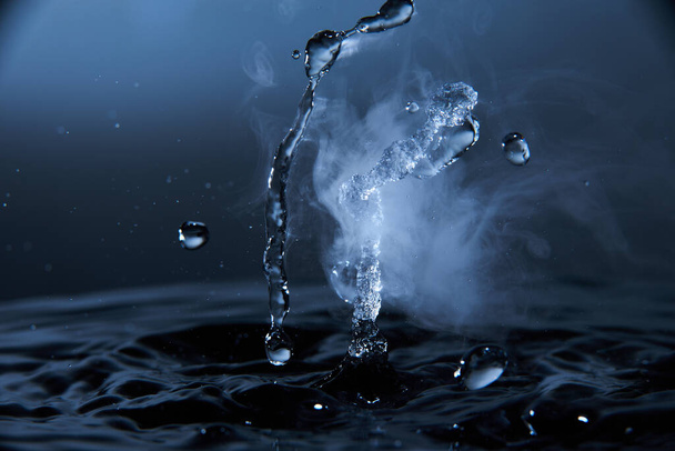 Boiling water splash with steam on dark blue background closeup. - Фото, зображення