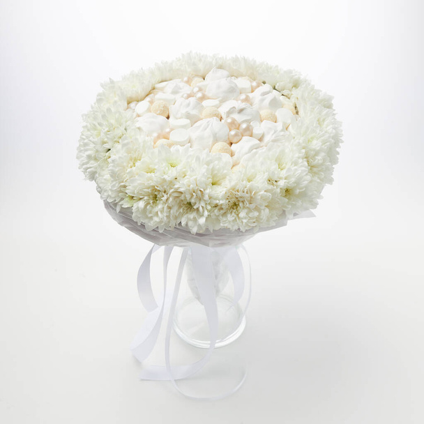 Biały bukiet pianek i czekoladek oprawionych w białe kwiaty stoi w wazonie na białym tle - Zdjęcie, obraz