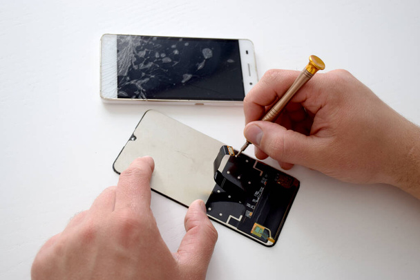 Les mains de l'homme fixent le panneau de téléphone du smartphone cassé
 - Photo, image