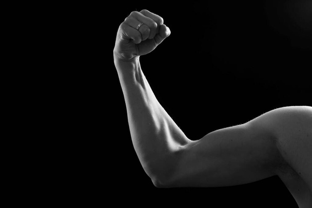 Bíceps musculares sobre fondo negro. Captura de estudio de los bíceps humanos. Cuerpo masculino sexy. Mano humana
. - Foto, imagen