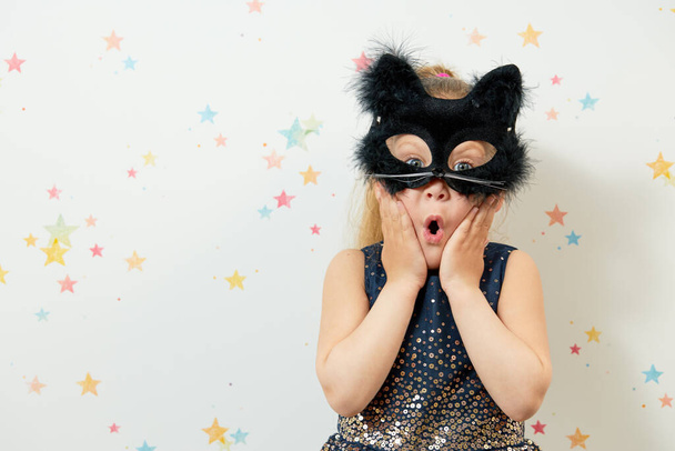 Happy Halloween 2021. Little girl child in black cat mask, carnival costume. Funny face - Photo, Image