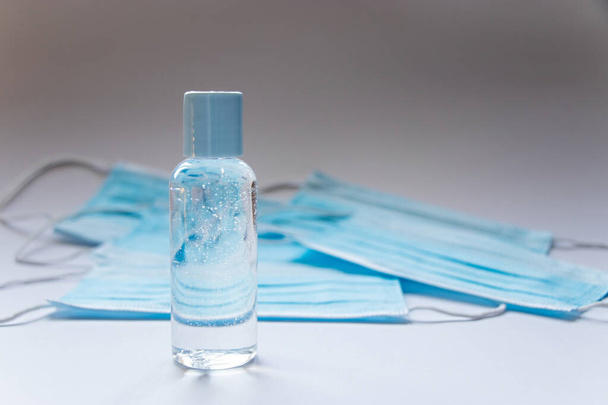Hand sanitizer gel in a plastic bottle and protective face mask with copy space. Concept of virus protection - Foto, Imagen