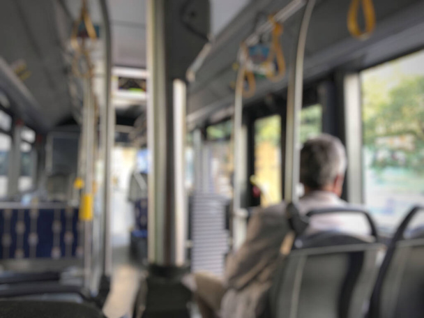 blurred background with a man sitting in an empty public bus - Zdjęcie, obraz