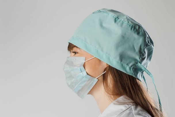 Close up portrait of pensive female doctor or nurse wearing protective mask and cap - Photo, Image