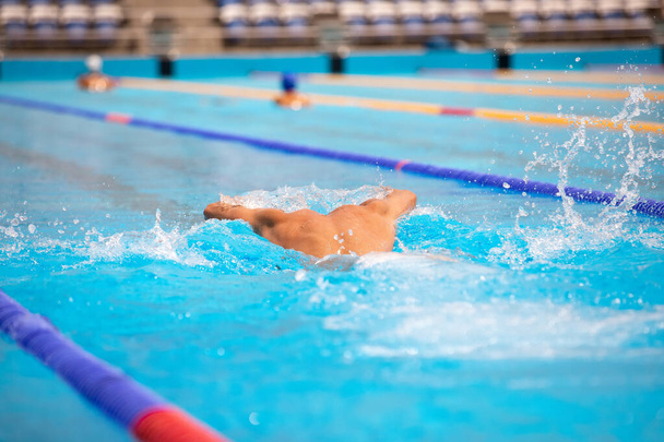 Athletic man swimming in butterfly style in the swimming pool with clear blue water. - Foto, Imagem