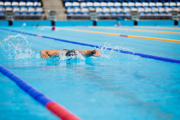 Sportlicher Mann schwimmt im Schmetterlingsstil im Schwimmbad mit klarem, blauem Wasser. - Foto, Bild